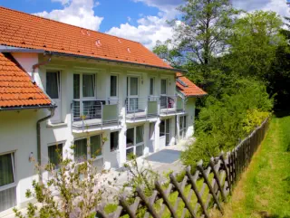 Rückansicht der Wohngemeinschaft mit Balkone und Terrassen im schönen Grün.